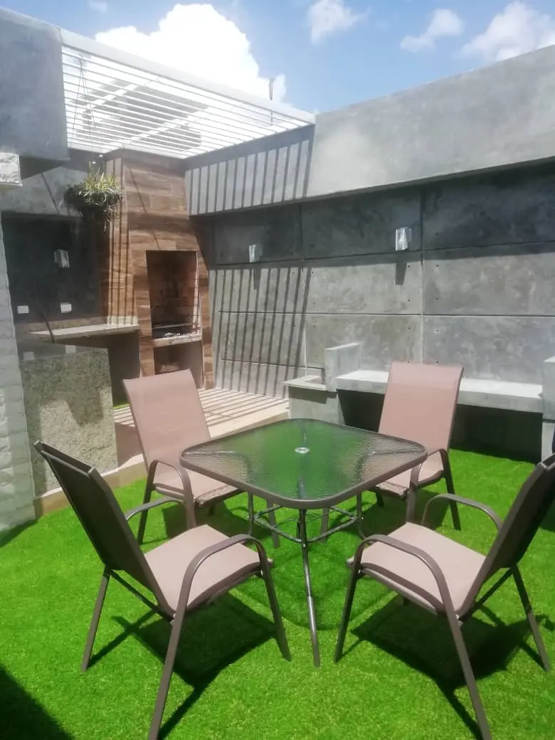 Terraza social ejecutada con mesa, sillas y área de parrilla